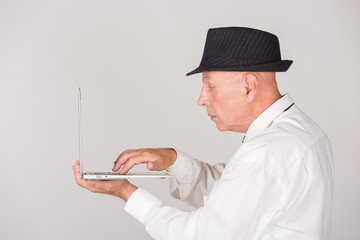 Älterer Mann hält Laptop / PC und arbeitet / zeigt mit Gestik Umgang