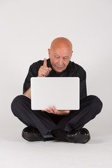 Älterer Mann mit Laptop / Computer sitzt und arbeitet / zeigt Mimik u Gestik