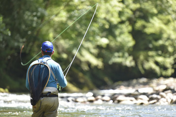 Flyfisherman fishing in mountain river © goodluz