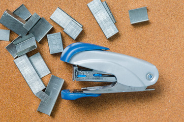stapler and staples on brown background,top view