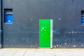 porta verde su muro grigio con finestre blu