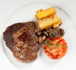 Pork chop steak with fried potatoes, mushrooms and tomato served