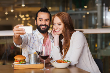 couple taking selfie by smartphone at restaurant