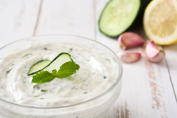 Tzatziki and ingredients on a white wooden table

