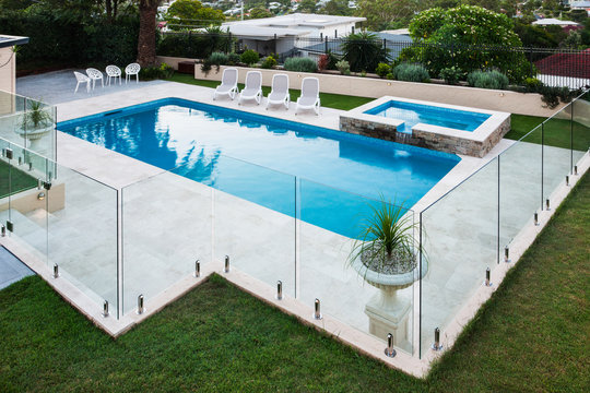 Modern swimming pool covered with glass panels beside a lawn