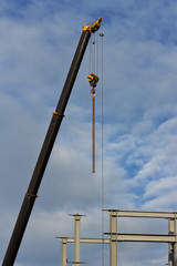 Crane and metal profile structure over blue sky