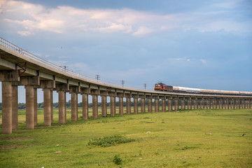 Train on the railway cross grass field meadow at Pasuk River Dam