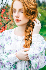 Naklejka premium Portrait of a beautiful redhead girl in the spring garden