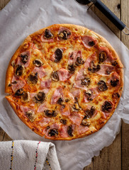 Delicious fresh pizza with mushrooms and bacon on a wooden backg