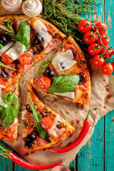 Homemade delicious pizza with bacon, tomatoes, olives and basil