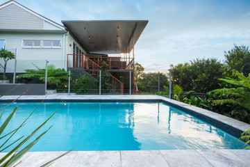 Modern swimming pool with blue water beside a house
