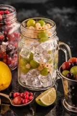 Fototapeta na wymiar Fresh berries with ice in mason jar on dark background