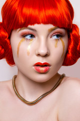 Woman in red and gold fashion make up and red hair on white background in studio photo. Art beauty photo