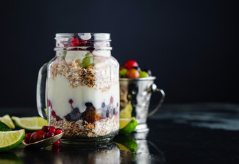 Muesli, fresh berries and yogurt in glass mason jar on wooden ta