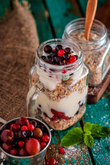 Muesli, fresh berries and yogurt in glass mason jar on wooden ta