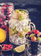 Fototapeta na wymiar Fresh berries with ice in mason jar on dark background