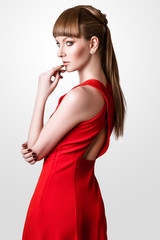 beautiful woman model posing in simple elegant red dress in the studio on white background