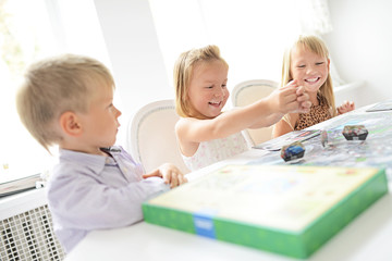 Cute preschoolers playing game on table
