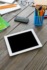 White tablet with blank screen on wooden table