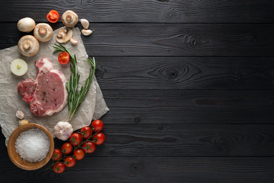 Raw pork cutlet with spices and Ingredients for grill or cooking on wooden background