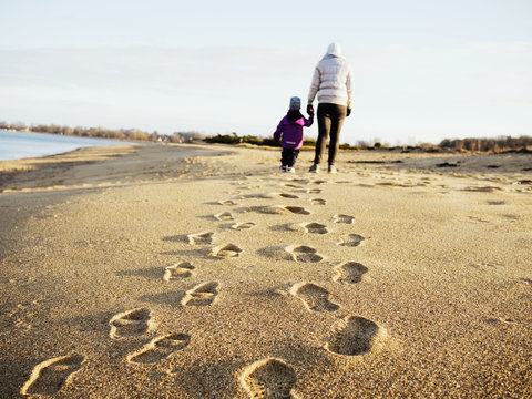 Rear view of mother with daughter walking at beach