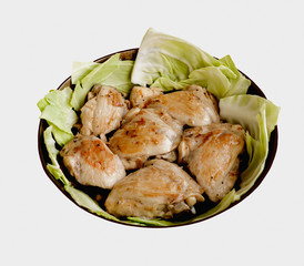 Fried chicken and leaves of cabbage in a frying pan