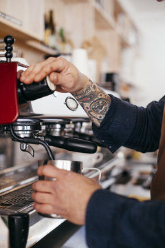 Cropped image of barista using coffee maker at cafeteria