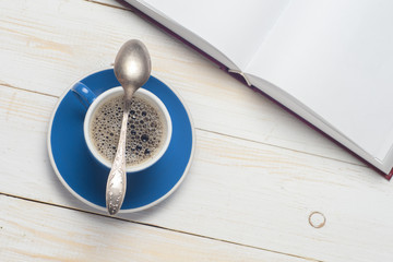 Open book and cup of coffee on a wooden table. Cozy background. Copy space for text. Top view