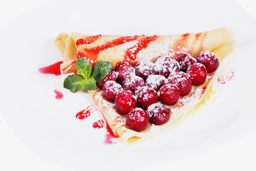 Pancakes stuffed cherries with mint on a plate