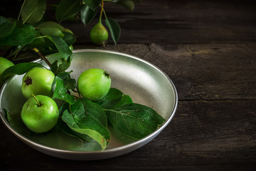 Fresh green apples with leaves on dark rusric background.