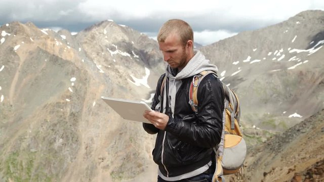 man's hands touching screen of digital tablet on the background of mountains