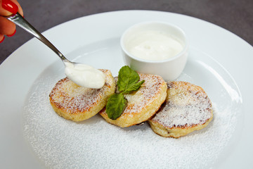 cheesecake slice decorated with mint leaf and sauce on white plate
