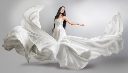 Fototapeta na wymiar beautiful young girl in flying white dress. Flowing fabric. Light white cloth flying in the wind