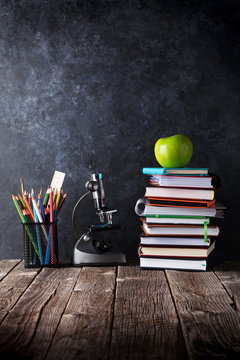 Notepads, supplies and apple in front of chalk board