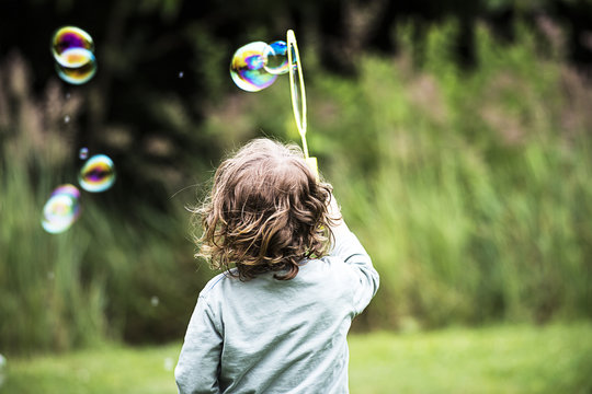 kind spielt mit Seifenblasen 