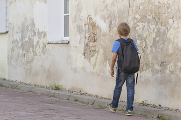 Obraz na płótnie Canvas Boy walking in the street with his backpack. Back view. People education, school, travel, leisure concept