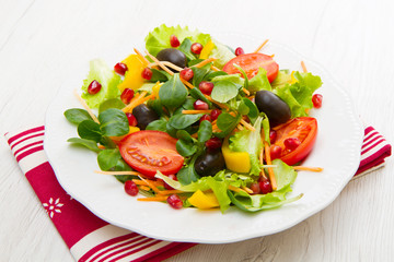 mixed salad with tomatoes in white plate on wood table