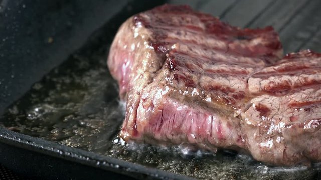 Beef Stake fried in a pan as high detailed 4K footage (close-up shot)