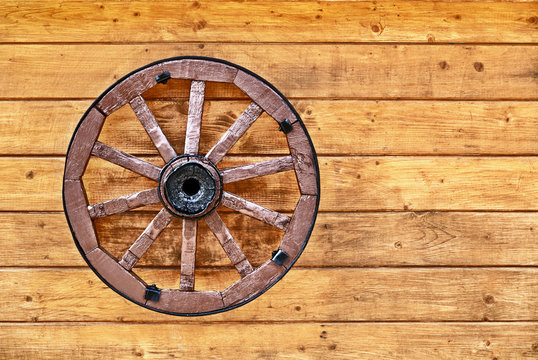 Old wagon wheel on a wooden wall