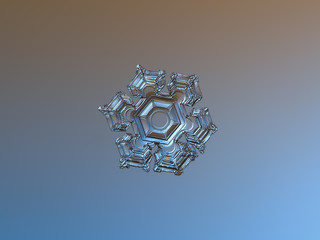 Snowflake, sparkling on brown - blue gradient background. This is macro photo of real snow crystal with large hexagonal center and relief surface, taken on large sheet of glass with back lighting.