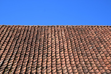 Dach mit roten Schindlen vor blauem Himmel