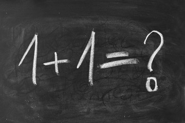 Napis kredą na tablicy szkolnej: 1+1. Równanie matematyczne
