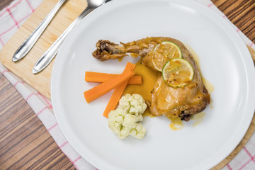Chicken cooked with orange marmalade, lemon and carrots .