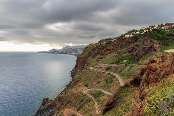 Naklejka premium winding road goes down to the beach Ponta do Garajau, Madeira, Portugal