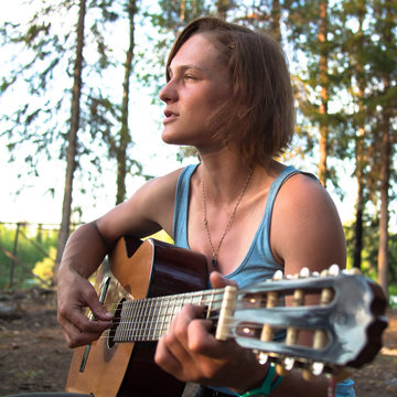 Woman with guitar closeup on a background of forest
