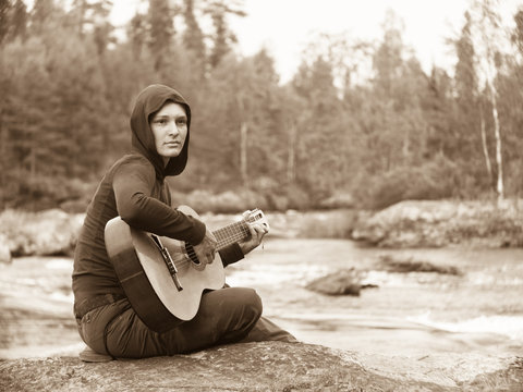 Toned image of a young woman with a guitar in his hands