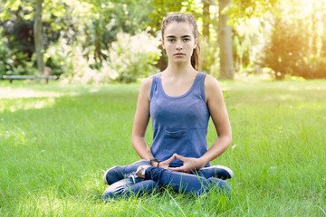 beautiful teenage girl meditates in a garden