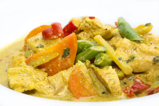 chicken curry with vegetables on a white plate in a restaurant
