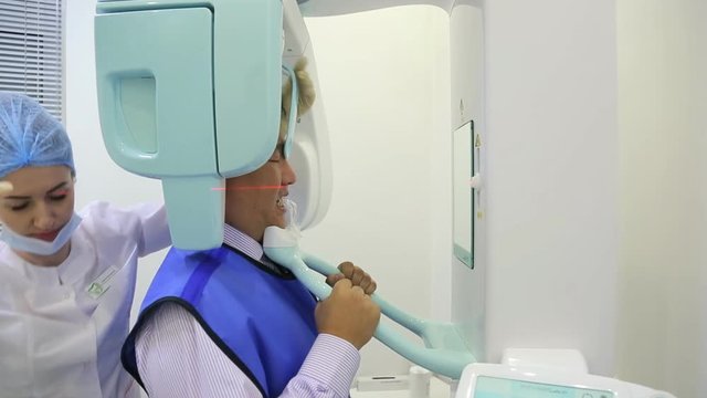 A nurse prepares a man of asian appearance to dental imaging.