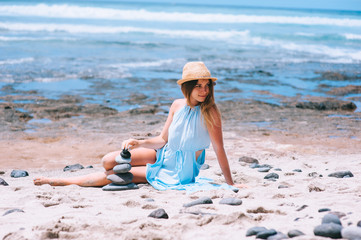 Fototapeta na wymiar Stack of pebble stones at the beach with a beautiful woman behin